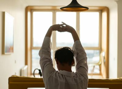 A man stretching his arms in a spacious, bright room.
